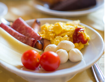 Breakfast Plate with Scrambled Eggs Bacon and Fresh Tomatoes at Memory Care Facility Breakfast Plate with Scrambled Eggs Bacon and Fresh Tomatoes at Memory Care Facility