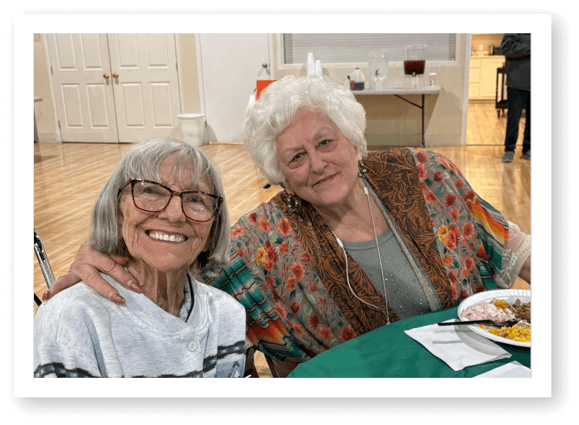 Two Elderly Women Smiling Together During Dining Event at Assisted Living Facility