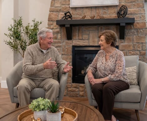 Elderly Couple Sitting Together by Stone Fireplace at Assisted Living Facility Elderly Couple Sitting Together by Stone Fireplace at Assisted Living Facility