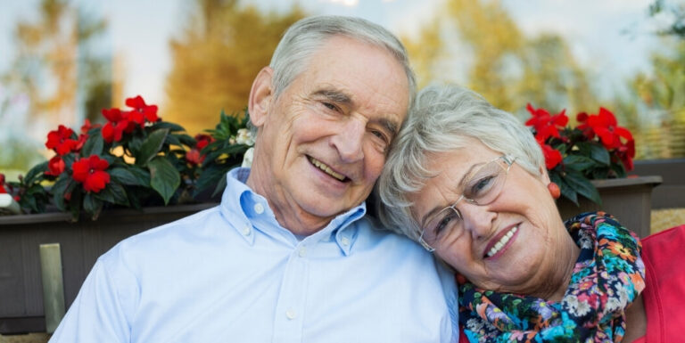 Elderly Couple Embracing near Flowers in Cleburne at Assisted Living Facility